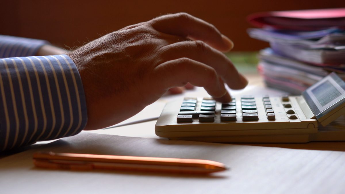 Accountant using calculator with paperwork.