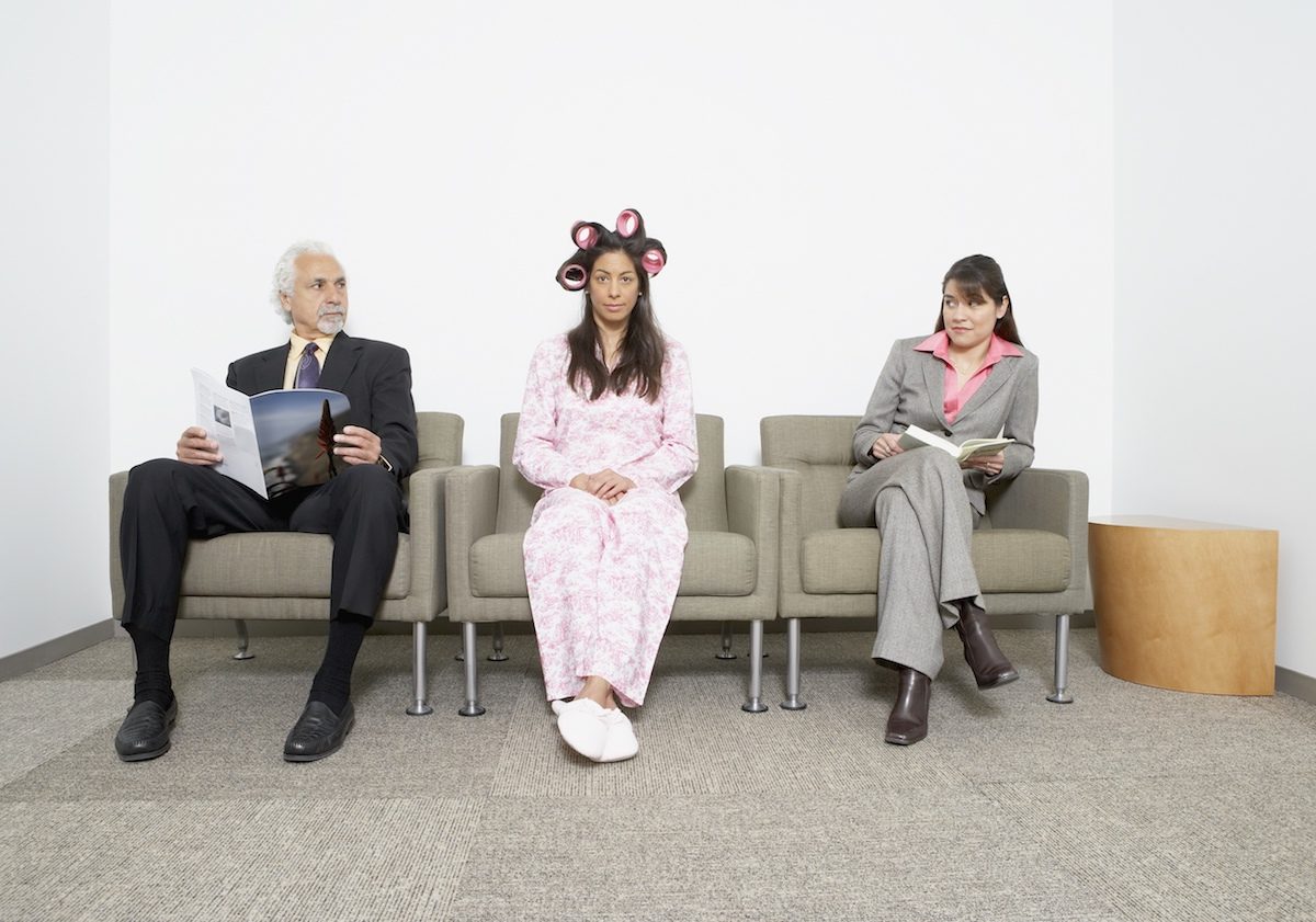 Hispanic woman in pajamas and curlers sitting next to business people Put some clothes on!