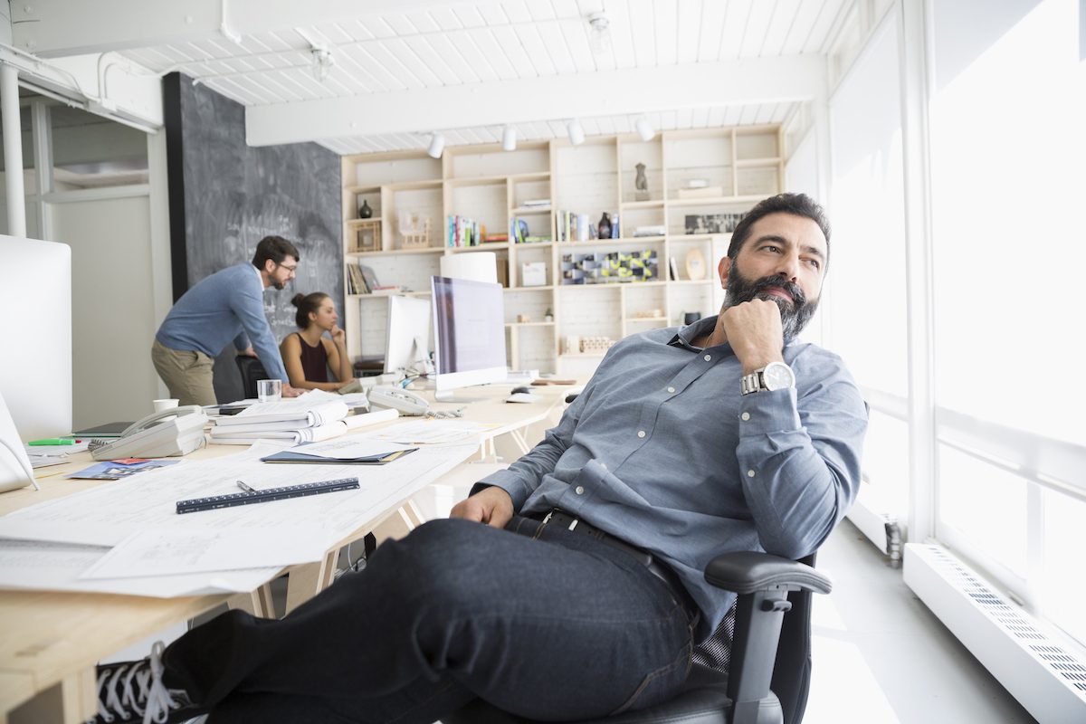 Pensive male architect looking through window in office