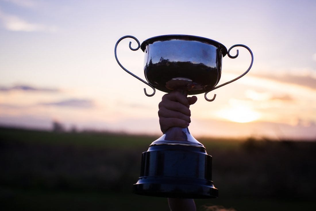 Child holding up school trophy, cup awarded