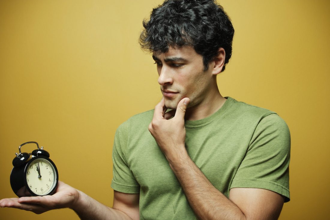 Young man holding alarm clock